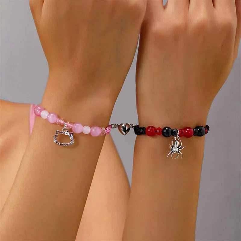 Bracelet set on wrists: pink heart charm beads and black/red spider charm