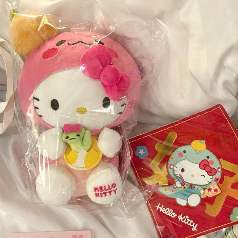 Hello Kitty plushie in clear bag, pink hood with bow, white face, green small character