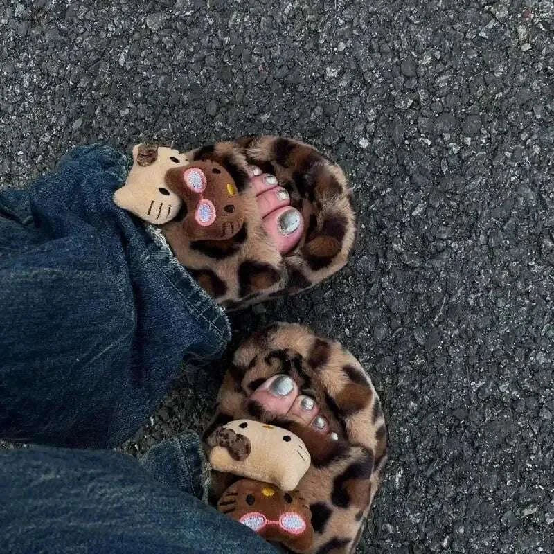 Fuzzy leopard print slippers with plush animal faces, shown on feet against asphalt