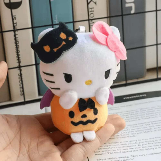 Plushie keychain with white cat plush, pink bow, pumpkin belly, black jack-o-lantern cap