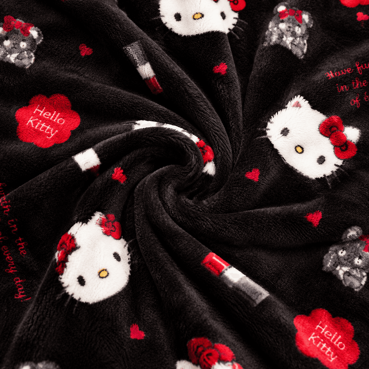 Black pajama pants fabric close-up with Hello Kitty faces, red bows, and candy cane motifs