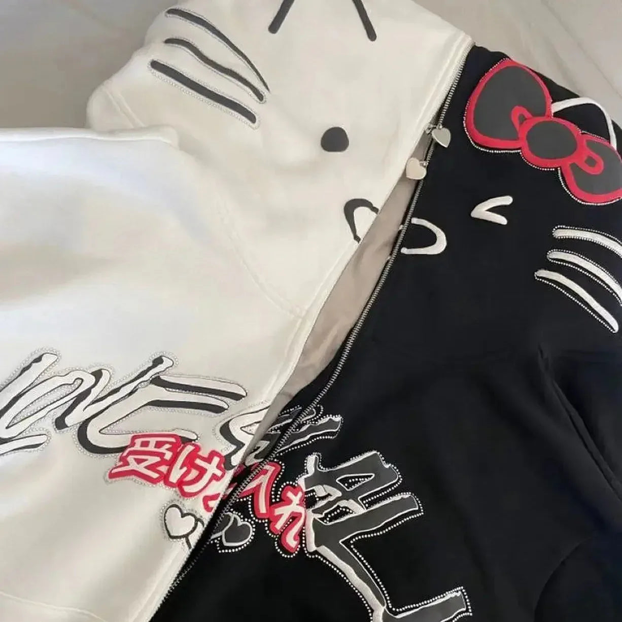 White and black Hello Kitty zip-up hoodie with cat face hood and chest logo print.