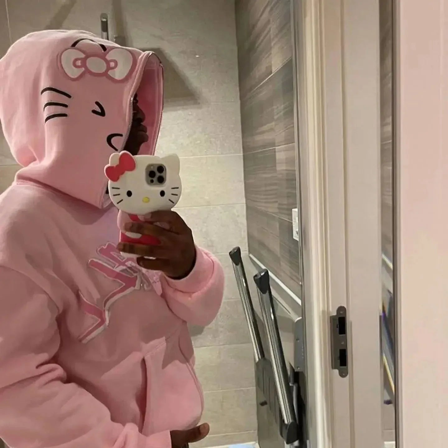 Pink Hello Kitty zip-up hoodie with cat face and red bow on hood; front zipper.