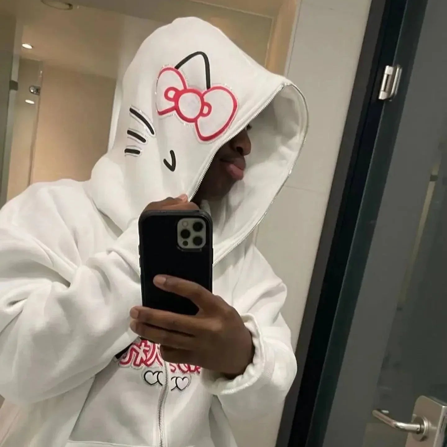White Hello Kitty zip-up hoodie with red bow cat face on hood; front zipper closure.
